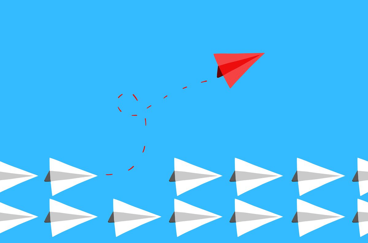 An illustration of a red paper airplane taking flight from a line of white paper airplanes.