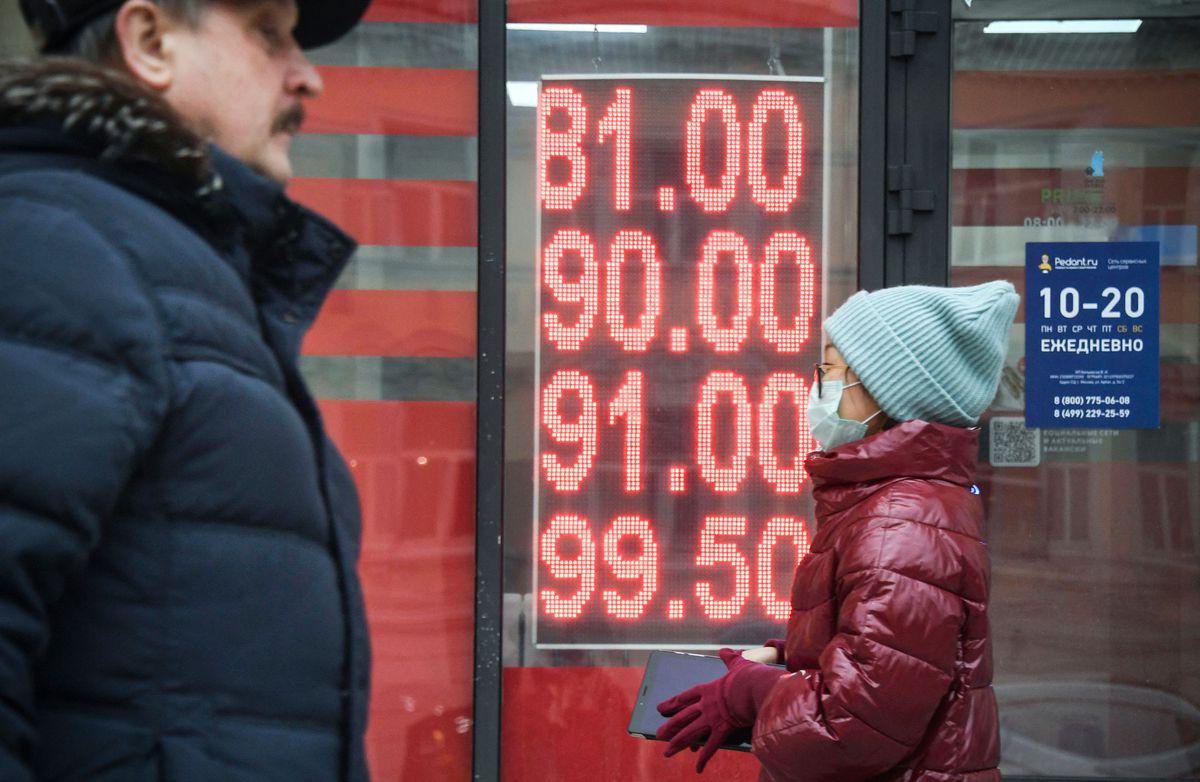 People in masks walking by a currency exchange.