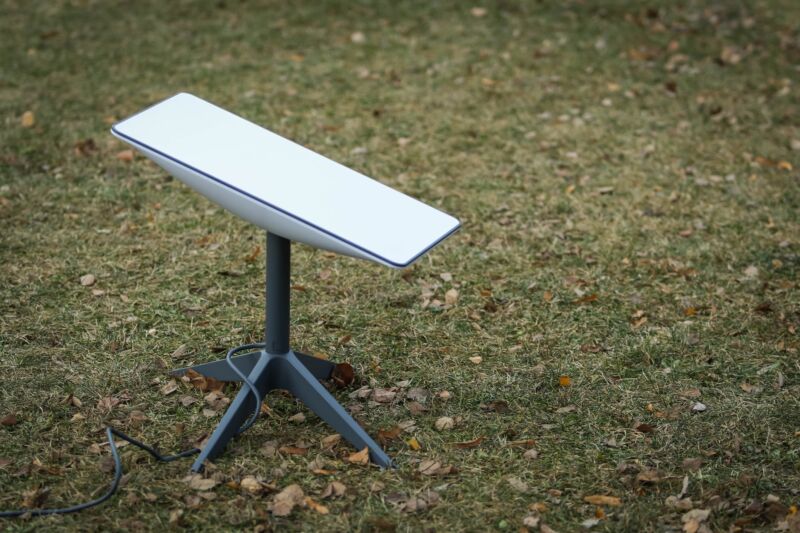 A Starlink satellite dish placed on the ground in a park.