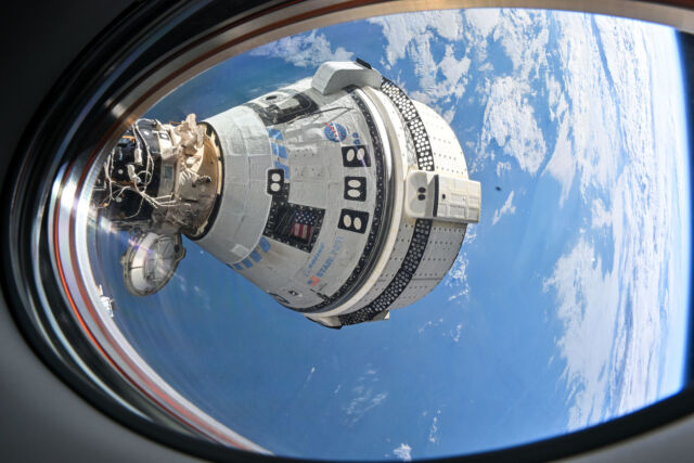 Boeing's Starliner spacecraft, seen docked at the International Space Station through the window of a SpaceX Dragon spacecraft.