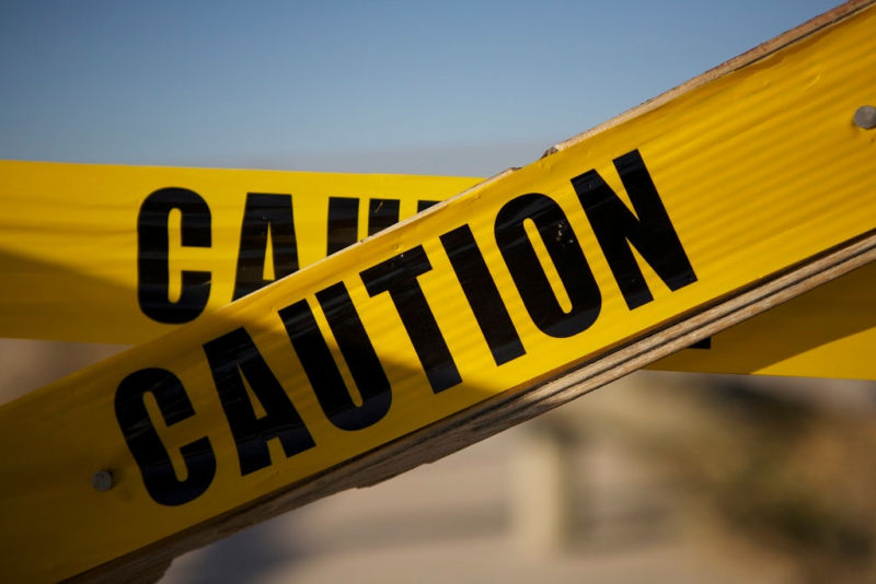 Close-up photo of police-style caution tape stretched across an out-of-focus background.