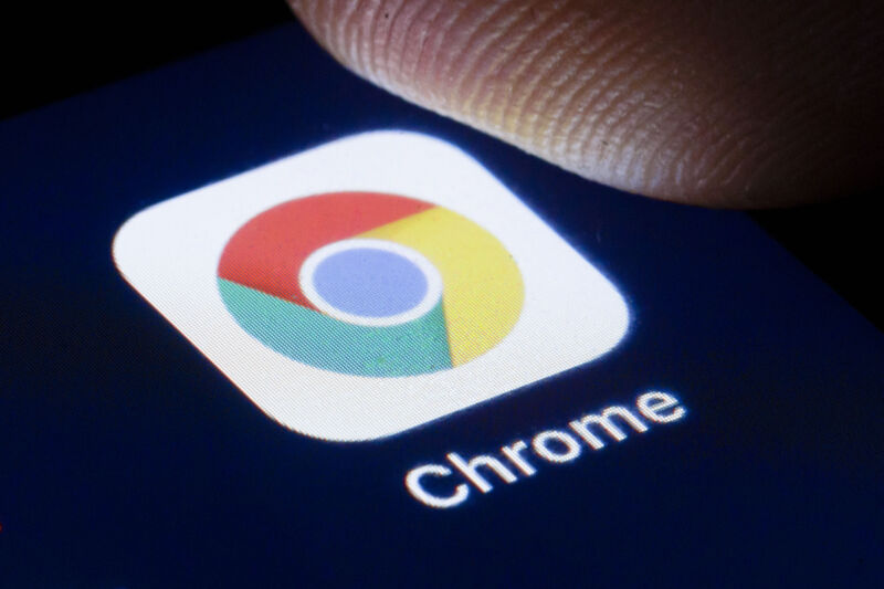 Extreme close-up photograph of finger above Chrome icon on smartphone.