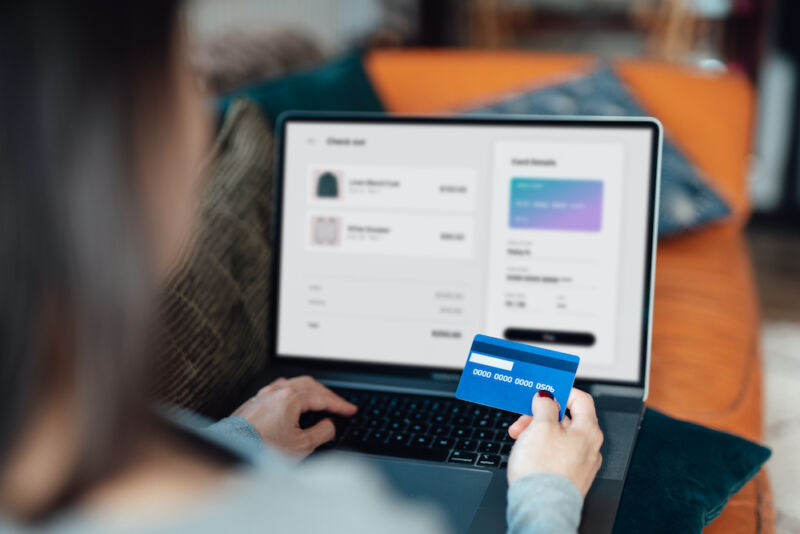 Stock photo of a woman using a laptop and a credit card to make a purchase.