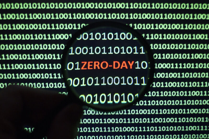The phrase Zero Day can be spotted on a monochrome computer screen clogged with ones and zeros.